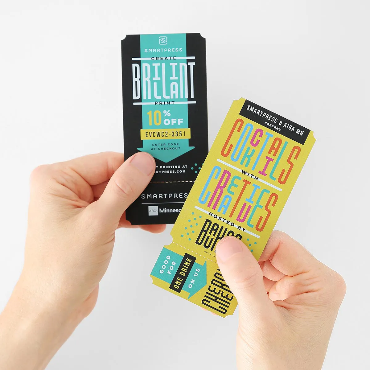Two hands holding drink tickets printed with custom white ink and yellow, black and green designs.