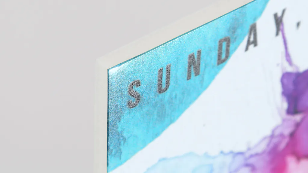 The corner of a custom foamcore sign printed with Sunday and a blue, white and purple design.