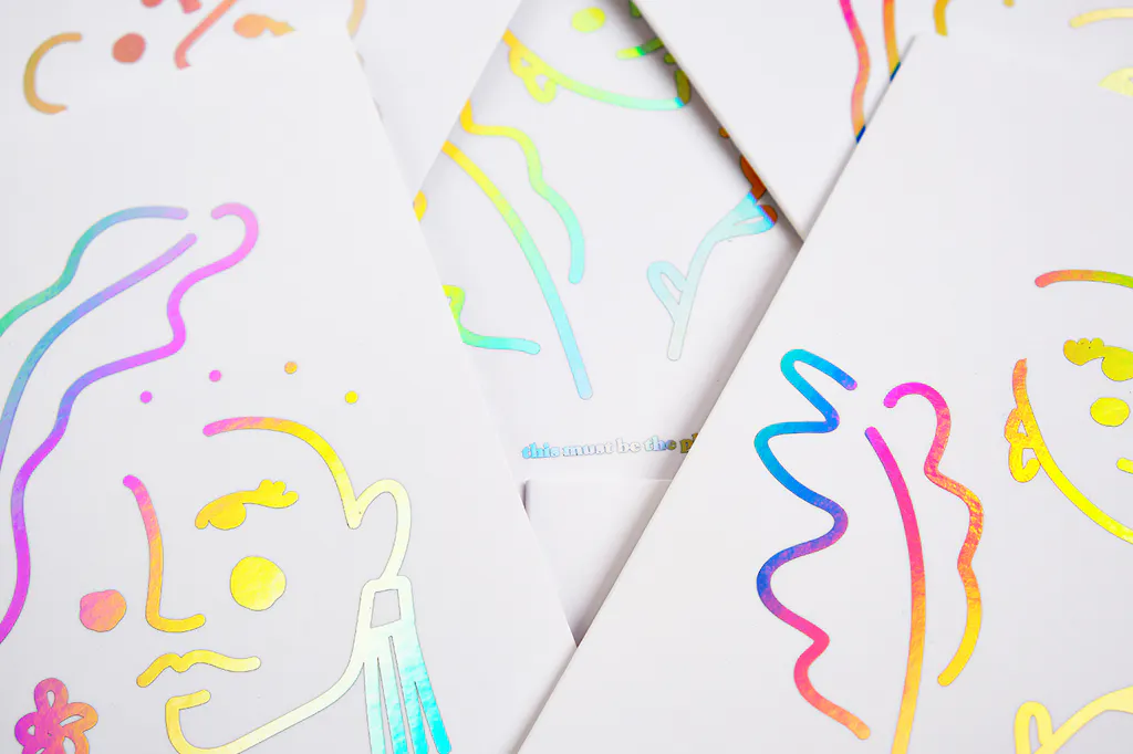 A pile of greeting cards with custom foil printing on the cover in holographic color.