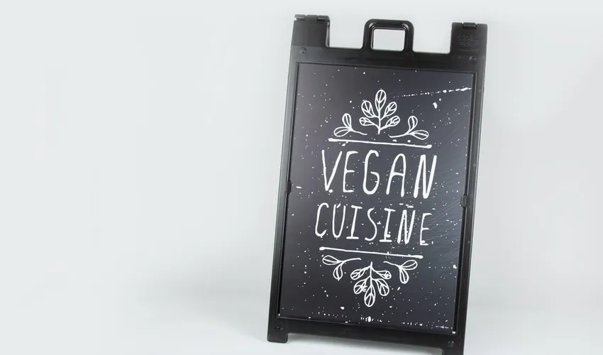 A custom sidewalk sign with a black frame and poster printed with Vegan Cuisine in white. 