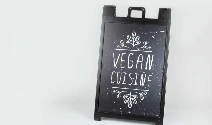 A custom sidewalk sign with a black frame and poster printed with Vegan Cuisine in white.