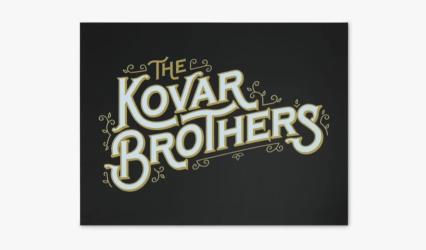 A PVC foam sign printed with a black background and The Kovar Brothers in gold and white.
