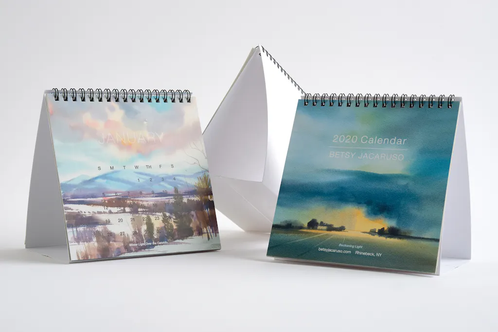Three custom desk calendars printed with landscape imagery and black wire bindings.