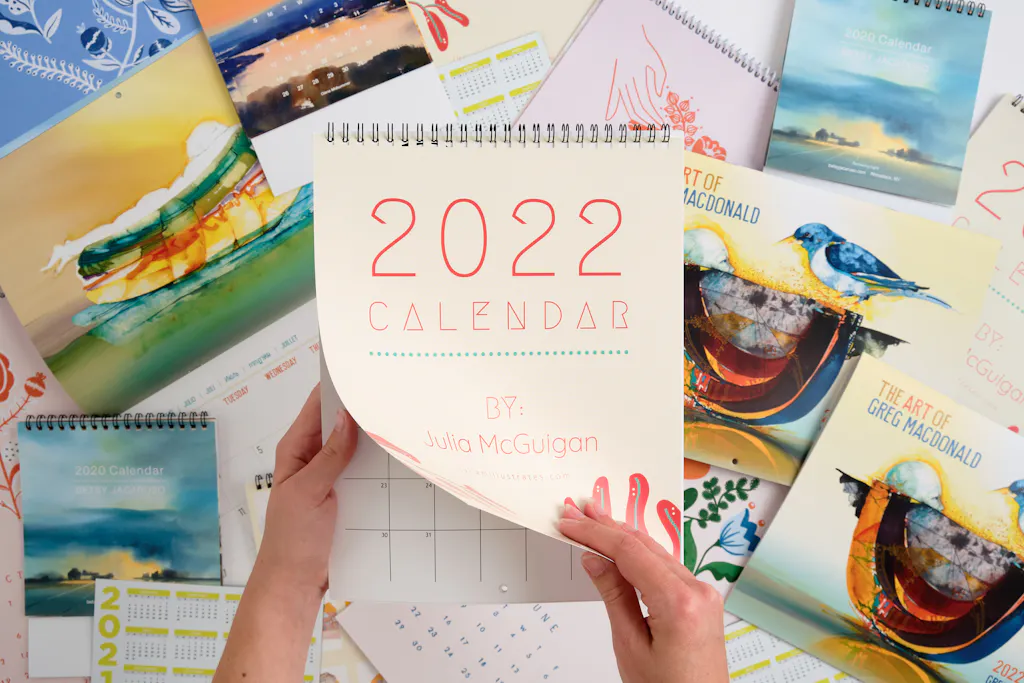 Two hands holding a wire bound calendar printed with 2022 Calendar on the front.