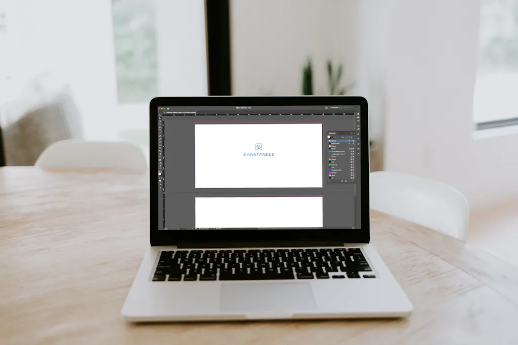 A laptop sitting on a wooden table and showing a design file setup with the Smartpress name and logo.