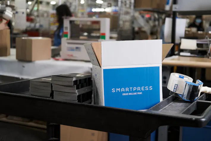 A Smartpress product box on a black cart with packing supplies in a production facility.