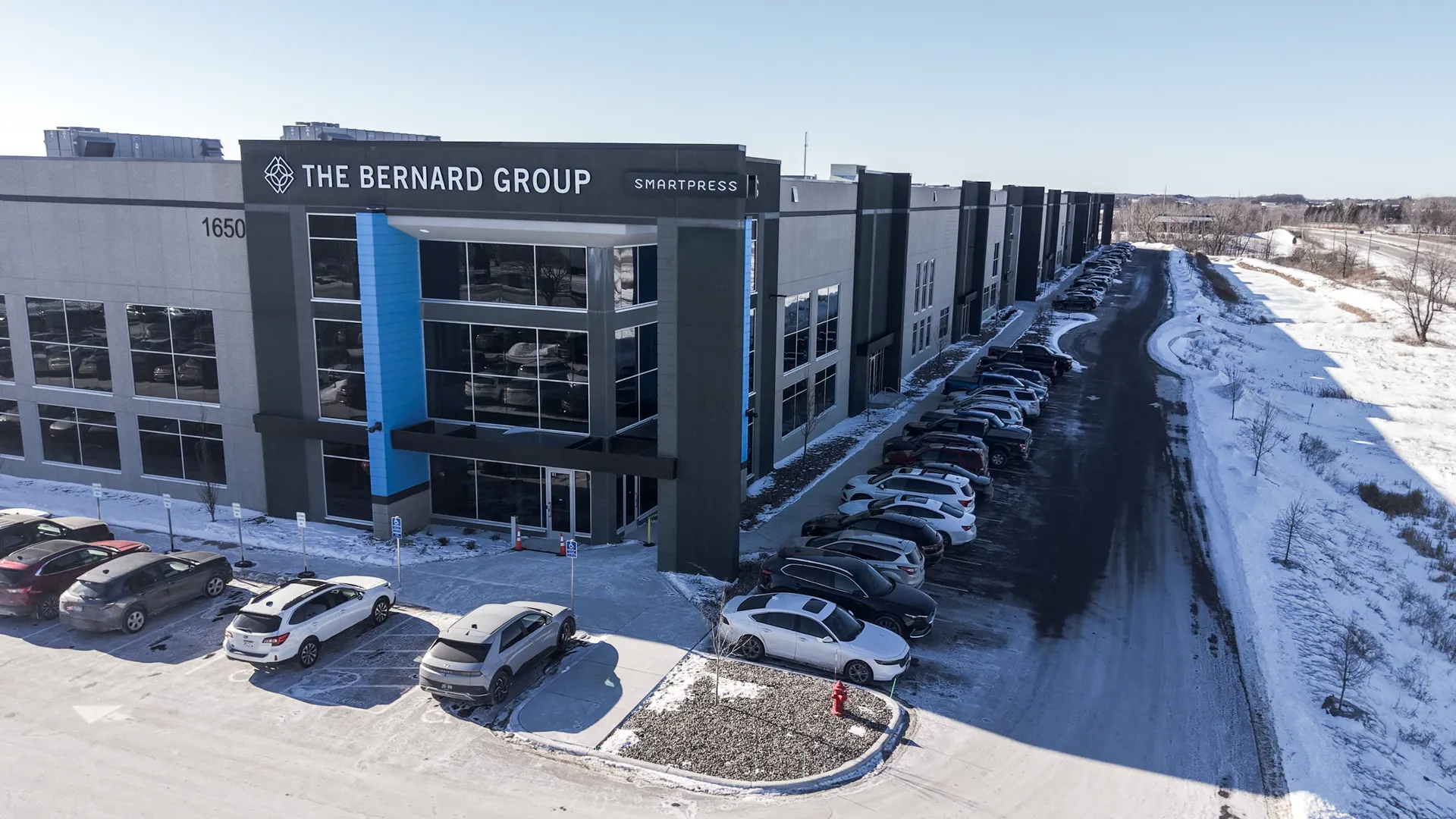 The outside of a gray and blue building with The Bernard Group and Smartpress on the top.