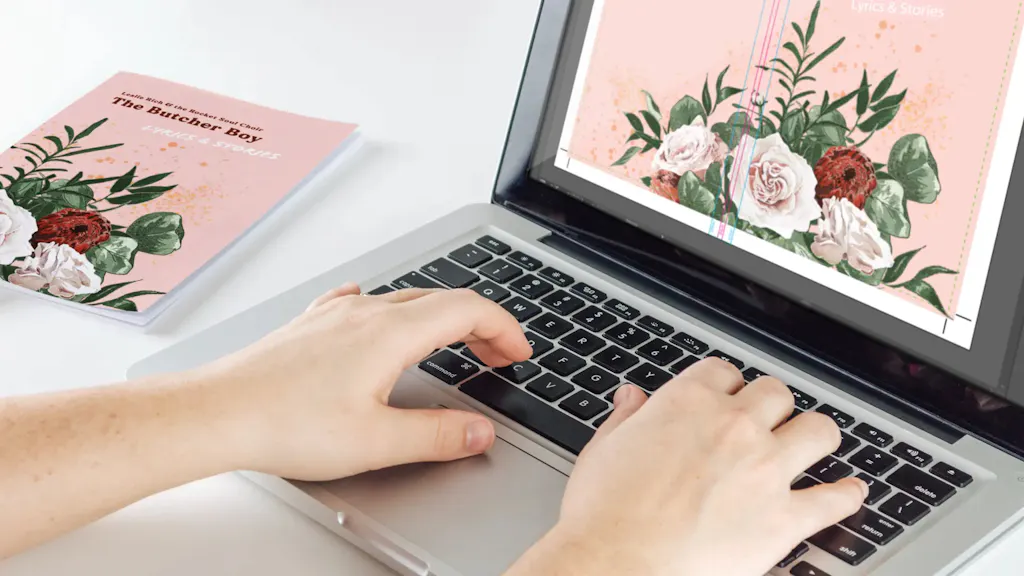 Two hands typing on a laptop with a soft print proof on the screen.