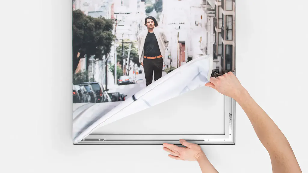 Two hands removing a silicone edge graphic from its aluminum frame.