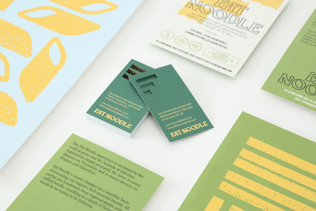 Custom business cards printed with a green die-cut design surrounded by other print marketing pieces.