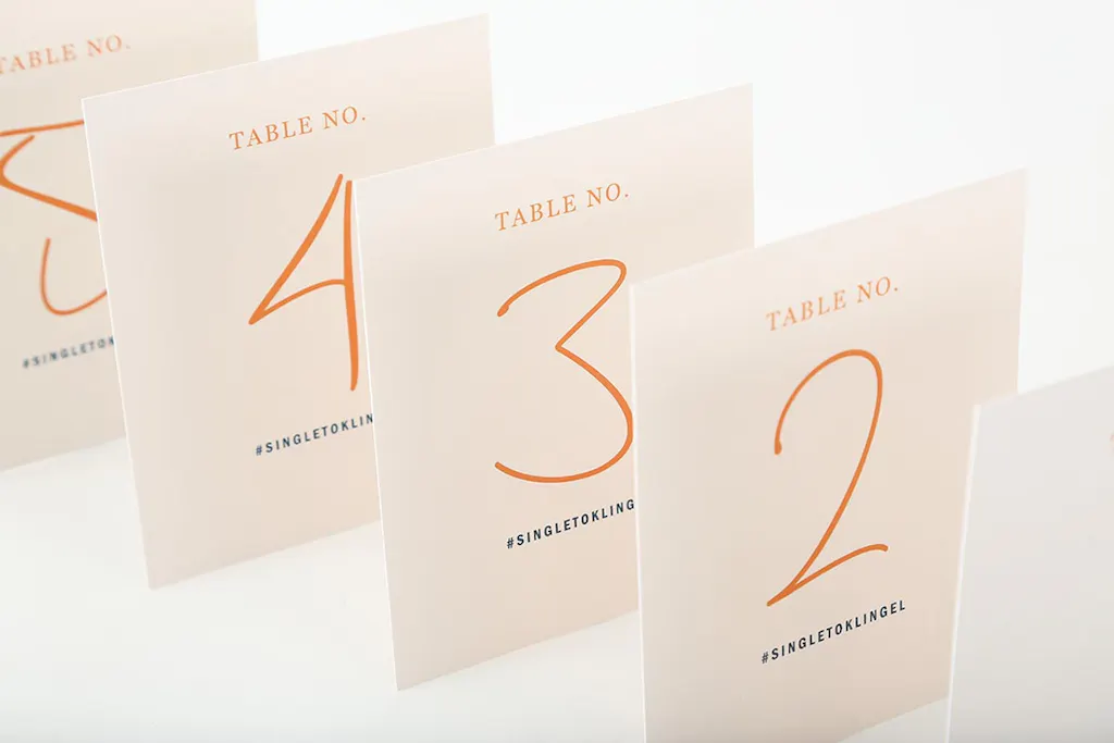 Five collated table number cards in peach color lined up in a row with #SINGLETOKLINGEL in black text.