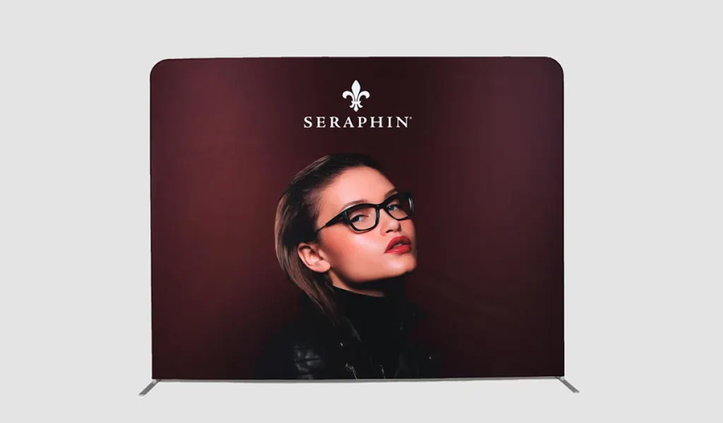 A tension fabric display with a woman wearing black-framed glasses and Seraphin on a maroon background.