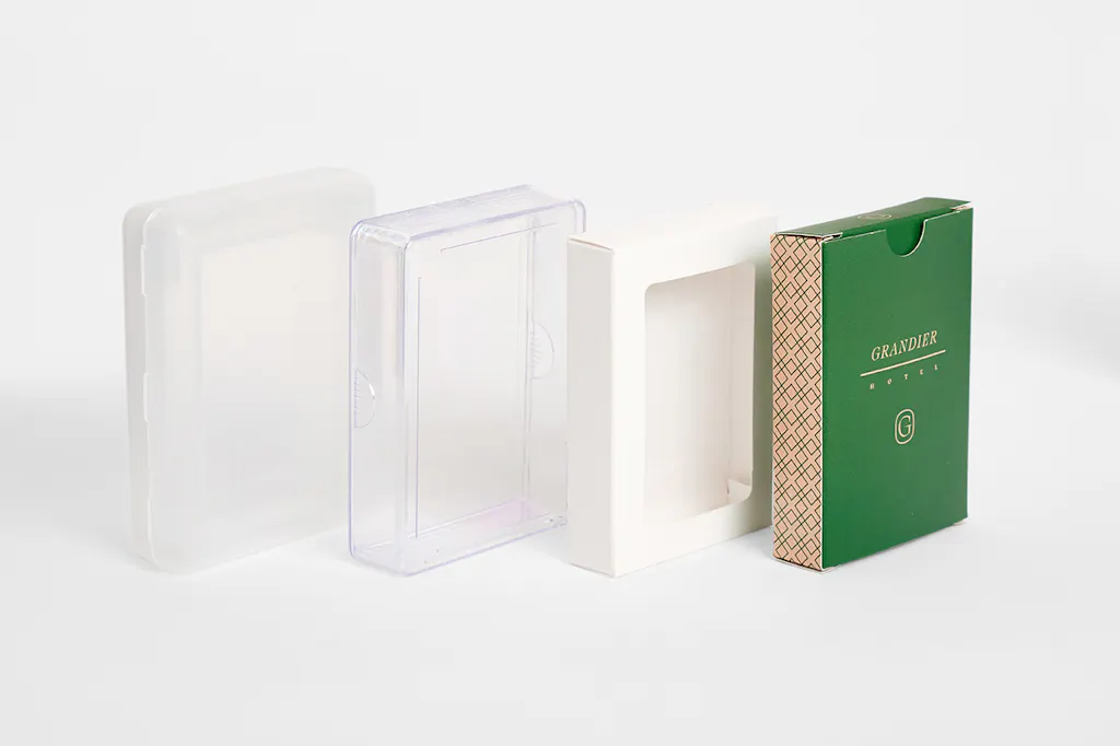 Four packaging options for playing cards lined up in a row, including clear cases and a box with a window.