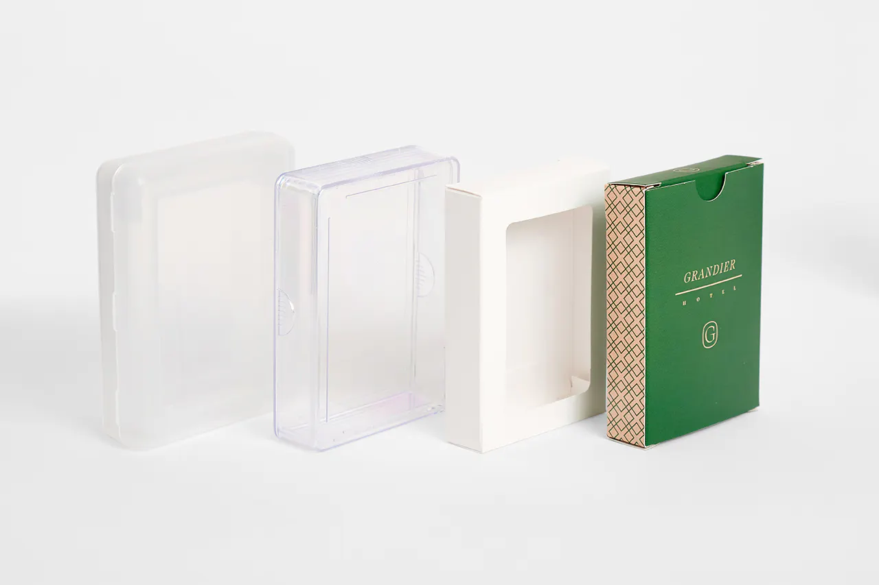 Four packaging options for playing cards lined up in a row, including clear cases and a box with a window.