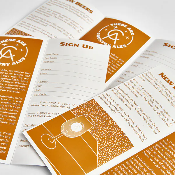 A pile of unfolded brochures printed with beer club details in white and orange.