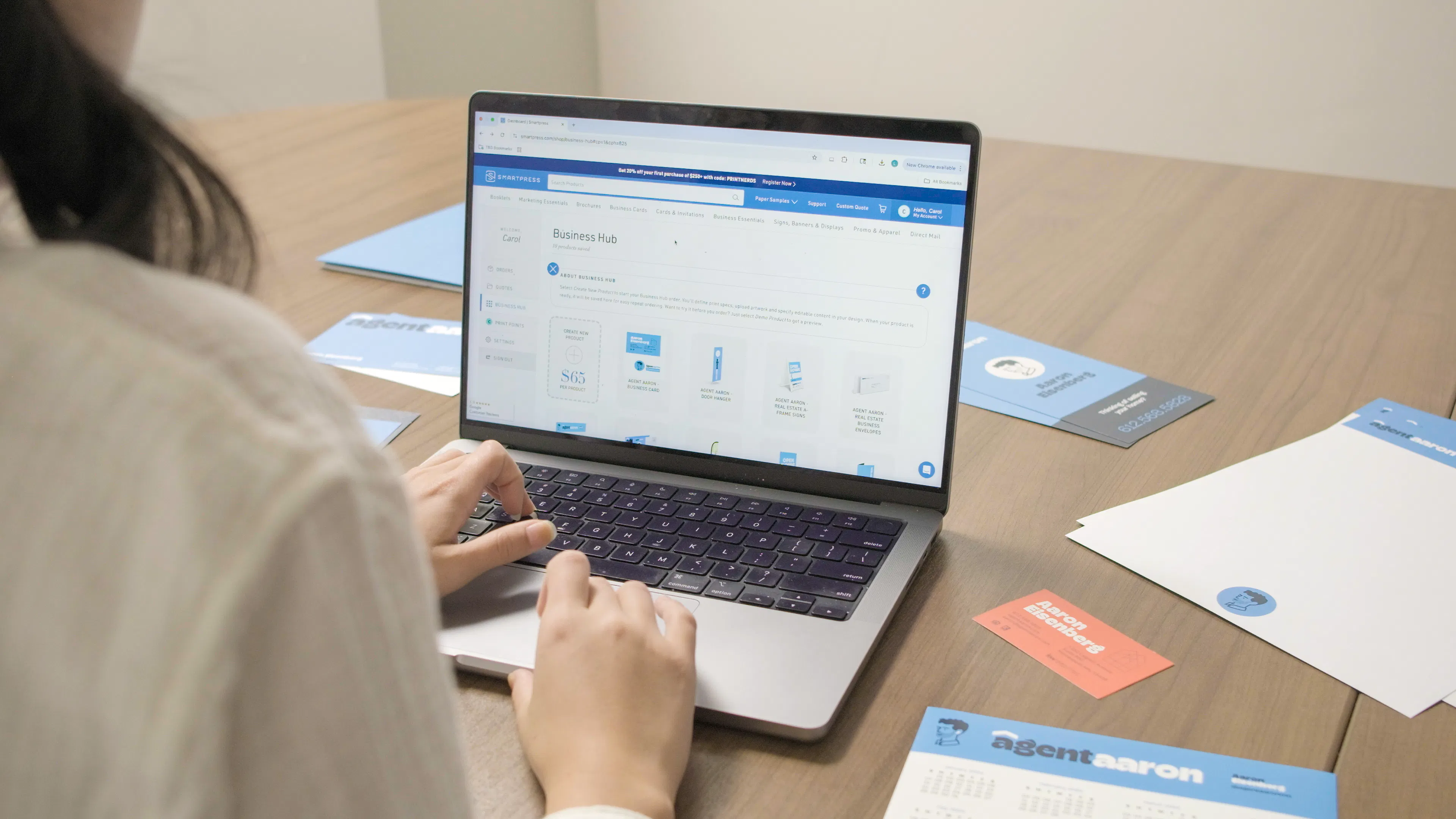 A woman typing on a laptop showing Smartpress' Business Hub on the screen.